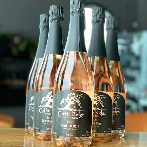 Row of Coffin Ridge sparkling rose bottles on a wooden surface with a blurred background